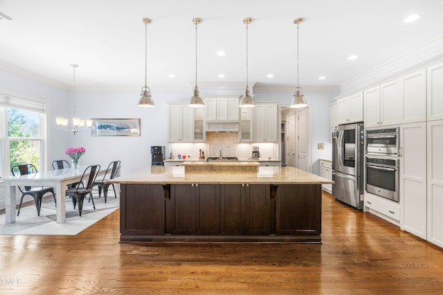 kitchen featuring stainless steel appliances, a breakfast bar area, dark hardwood / wood-style floors, a spacious island, and pendant lighting