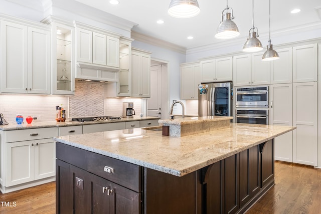 kitchen featuring white cabinetry, appliances with stainless steel finishes, hardwood / wood-style flooring, and a center island with sink