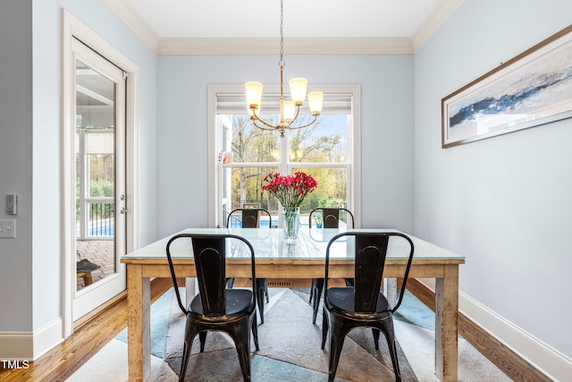 dining area featuring light wood-type flooring, a chandelier, and crown molding