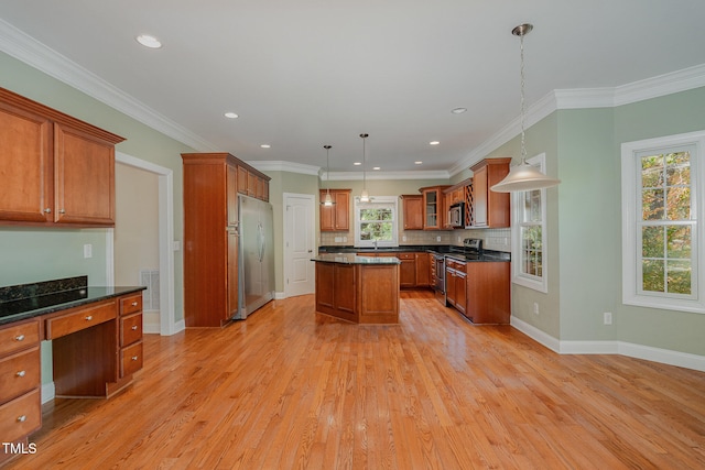 kitchen featuring appliances with stainless steel finishes, decorative light fixtures, a kitchen island, and light hardwood / wood-style flooring