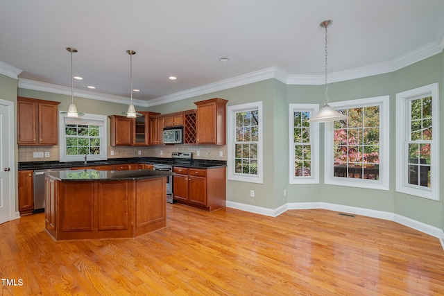 kitchen featuring light wood-type flooring, stainless steel appliances, hanging light fixtures, and a healthy amount of sunlight