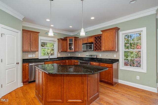 kitchen featuring stainless steel appliances, decorative light fixtures, a healthy amount of sunlight, and a center island