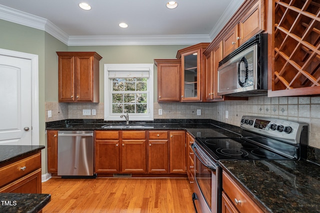 kitchen featuring stainless steel appliances, sink, light wood-type flooring, and ornamental molding