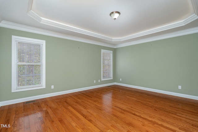 spare room featuring a tray ceiling, hardwood / wood-style flooring, and ornamental molding