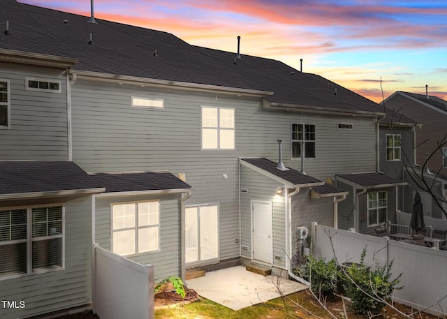 back house at dusk featuring a patio