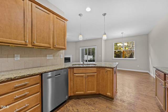 kitchen featuring light wood-type flooring, light stone counters, sink, a notable chandelier, and dishwasher