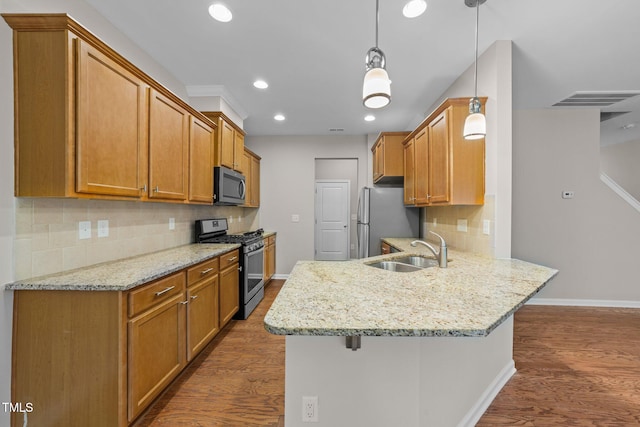 kitchen featuring sink, hanging light fixtures, appliances with stainless steel finishes, kitchen peninsula, and dark hardwood / wood-style floors