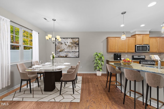 dining room featuring hardwood / wood-style floors, a notable chandelier, and sink