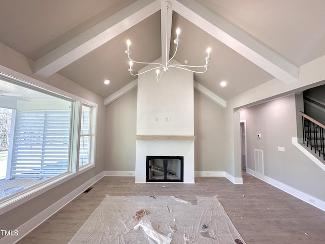 unfurnished living room with hardwood / wood-style floors, a large fireplace, lofted ceiling with beams, and a notable chandelier