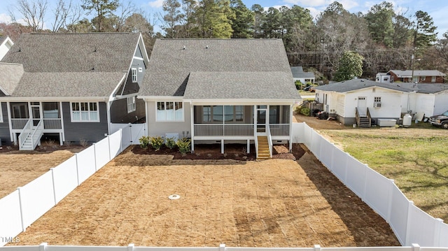 view of front facade featuring a shingled roof, entry steps, a sunroom, a fenced backyard, and a front lawn