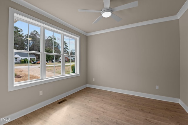 empty room with crown molding, visible vents, ceiling fan, light wood-type flooring, and baseboards