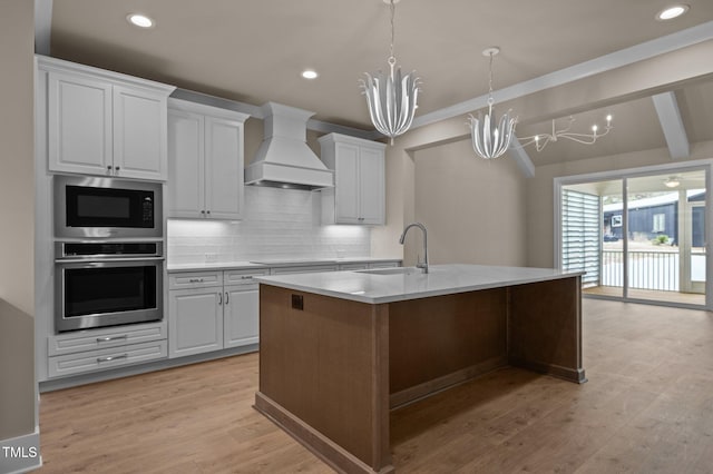 kitchen with a sink, stainless steel oven, custom exhaust hood, built in microwave, and tasteful backsplash