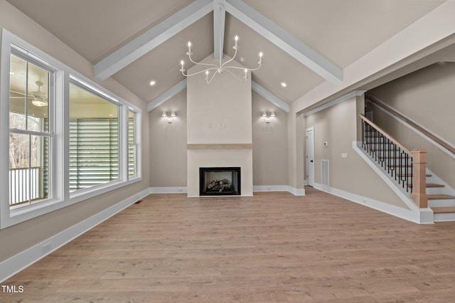 unfurnished living room featuring light wood-style flooring, stairway, vaulted ceiling with beams, a fireplace, and a notable chandelier