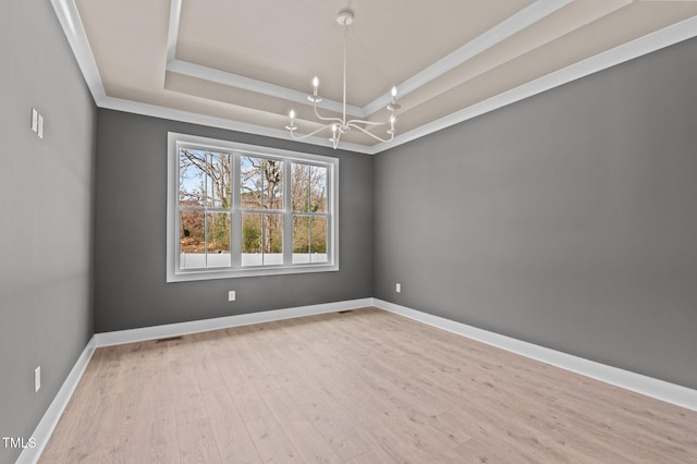 unfurnished room with baseboards, a raised ceiling, ornamental molding, wood finished floors, and a notable chandelier