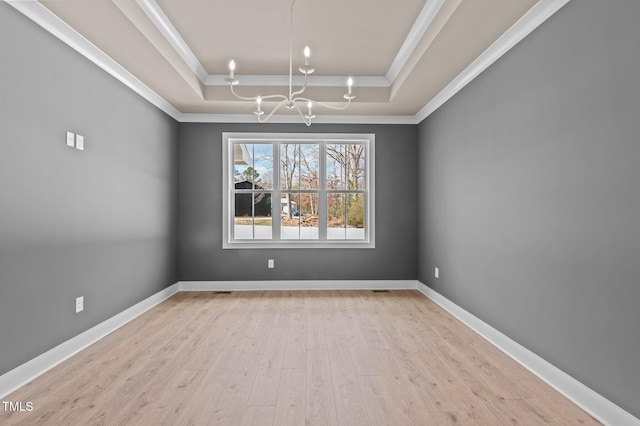 empty room featuring baseboards, a raised ceiling, wood finished floors, crown molding, and a chandelier