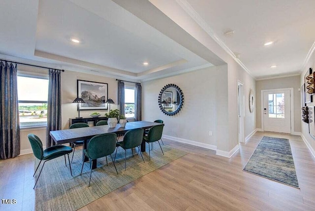 dining room with light wood-type flooring, a wealth of natural light, and crown molding