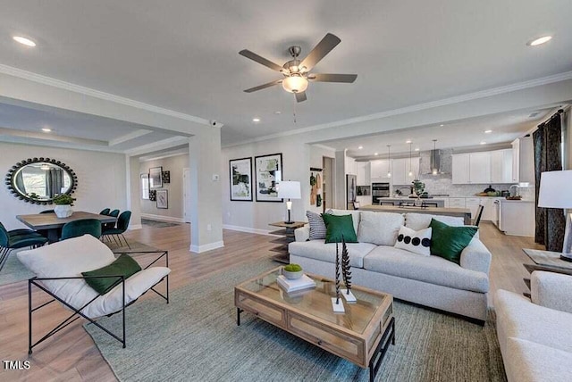 living room featuring ceiling fan, light wood-type flooring, and ornamental molding