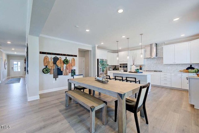 dining area with ornamental molding and light hardwood / wood-style floors