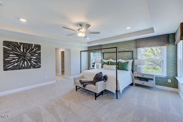 carpeted bedroom with ceiling fan and a tray ceiling