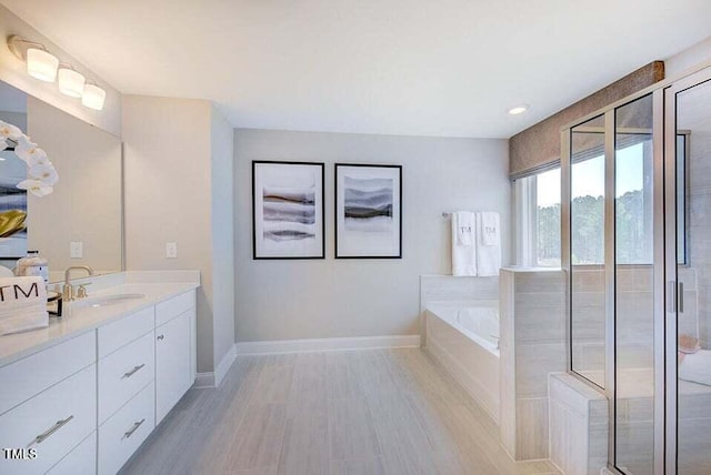 bathroom with hardwood / wood-style flooring, vanity, and plus walk in shower