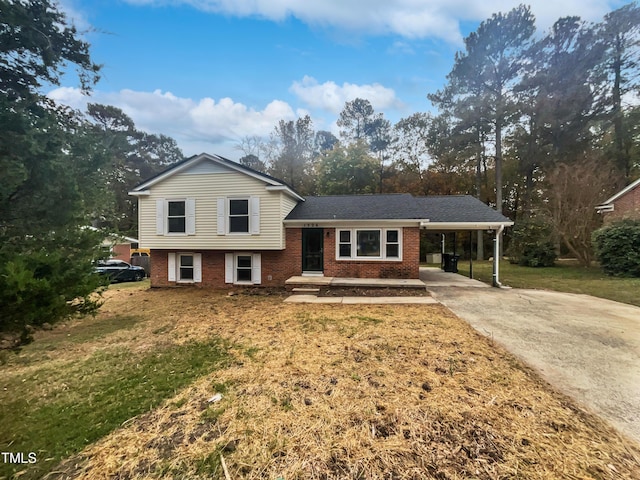 tri-level home with brick siding, a shingled roof, concrete driveway, a front yard, and an attached carport