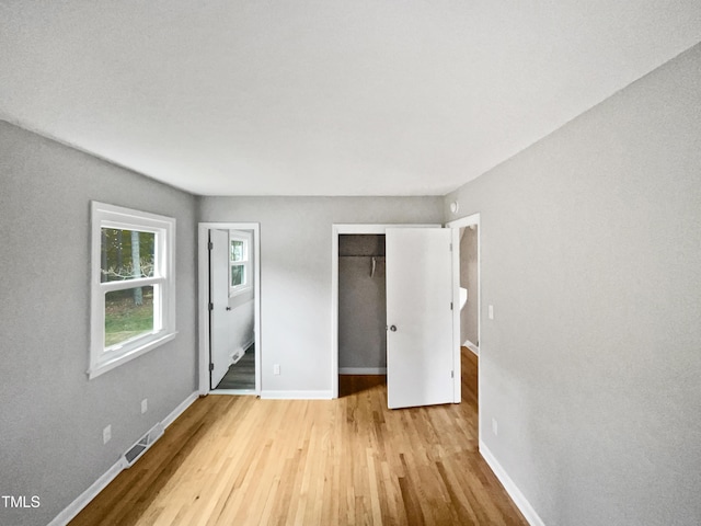 unfurnished bedroom with baseboards, a closet, visible vents, and wood finished floors