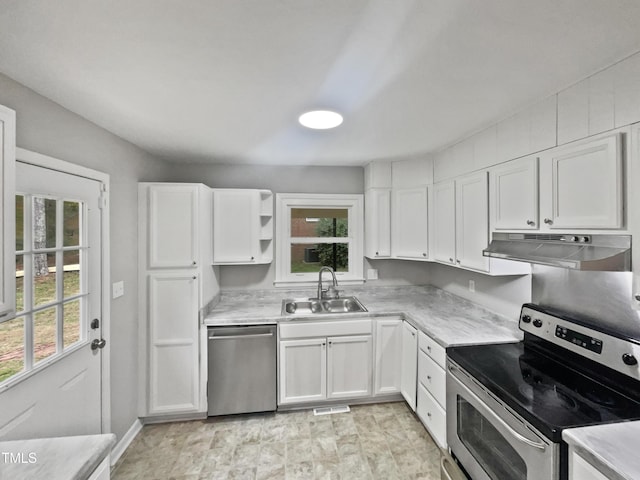 kitchen with stainless steel appliances, under cabinet range hood, a sink, light countertops, and white cabinets