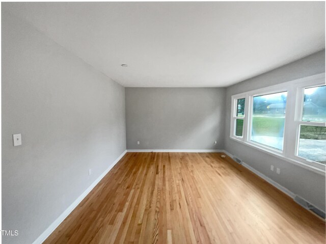 spare room featuring light wood-style floors and baseboards