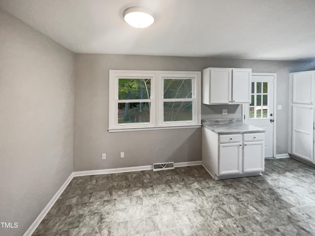 kitchen featuring a wealth of natural light, visible vents, baseboards, and white cabinetry