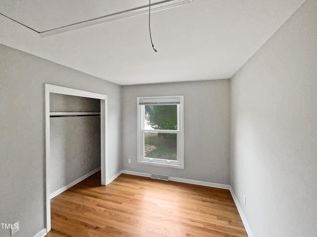 unfurnished bedroom with a closet, light wood-style floors, visible vents, and baseboards