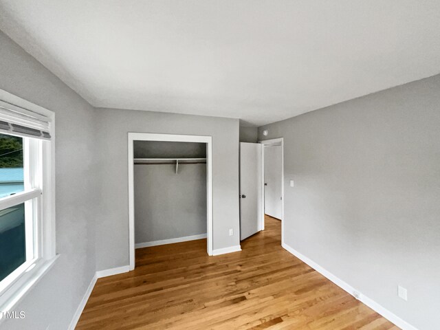 unfurnished bedroom with a closet, wood finished floors, and baseboards