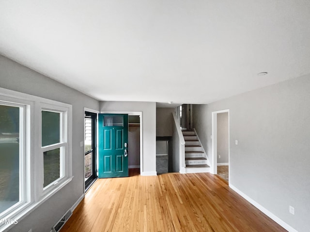 foyer entrance featuring visible vents, wood finished floors, baseboards, and stairs