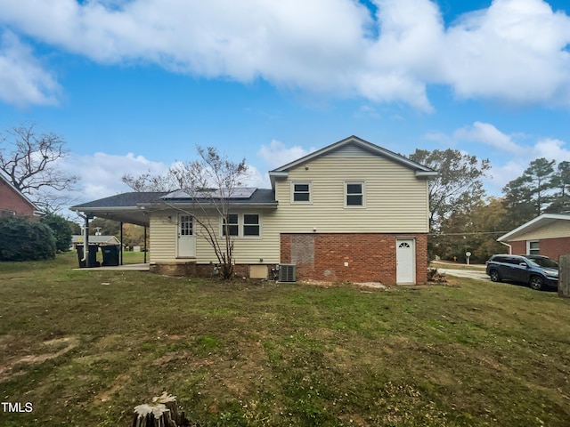 rear view of property featuring solar panels, brick siding, and a lawn