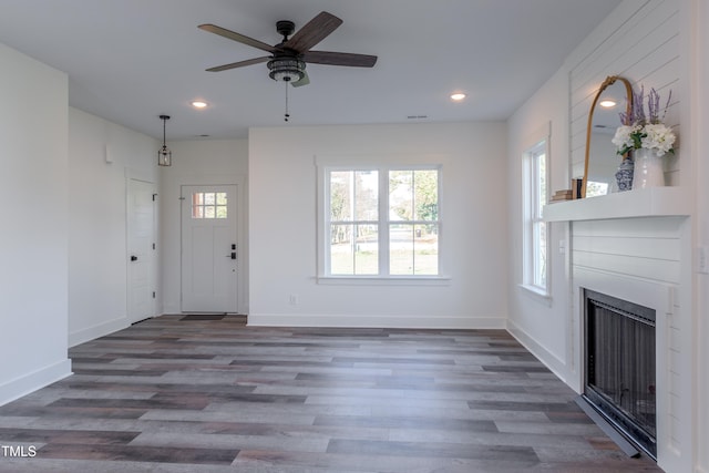 unfurnished living room featuring dark wood-type flooring, ceiling fan, and a healthy amount of sunlight