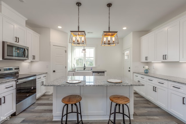 kitchen featuring white cabinets, appliances with stainless steel finishes, a kitchen island, and dark hardwood / wood-style flooring