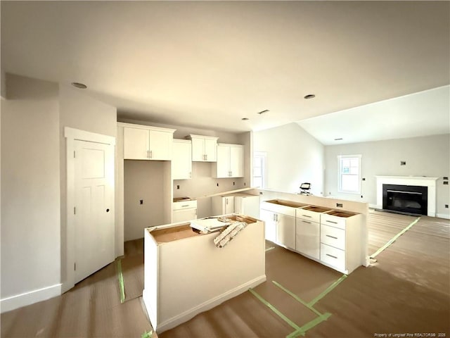 kitchen with hardwood / wood-style flooring, lofted ceiling, a center island, and white cabinets