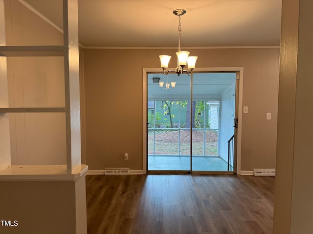 unfurnished dining area featuring wood walls, a notable chandelier, dark hardwood / wood-style flooring, and ornamental molding