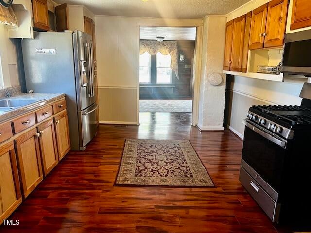 kitchen with stainless steel appliances, a textured ceiling, sink, and dark wood-type flooring