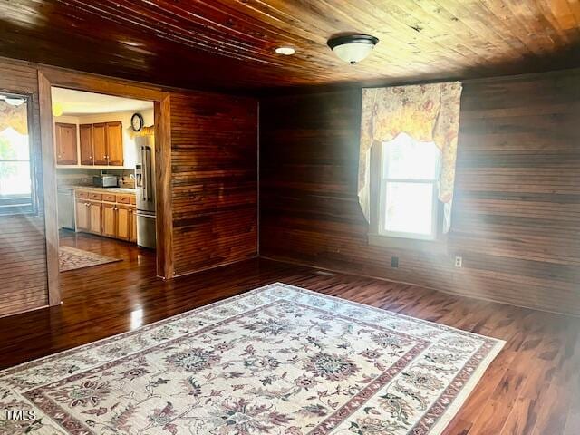 empty room with dark wood-type flooring, wooden walls, and wooden ceiling