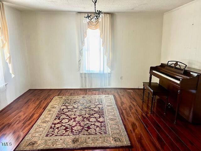 interior space featuring dark wood-type flooring, a textured ceiling, and a notable chandelier