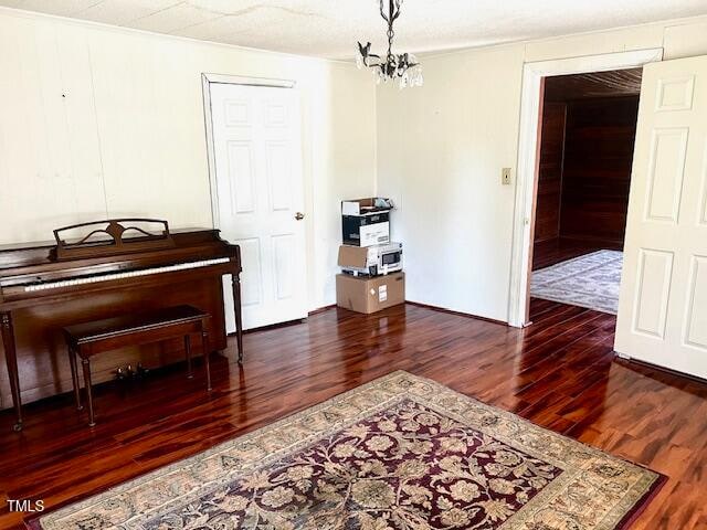 miscellaneous room featuring dark wood-type flooring and a chandelier