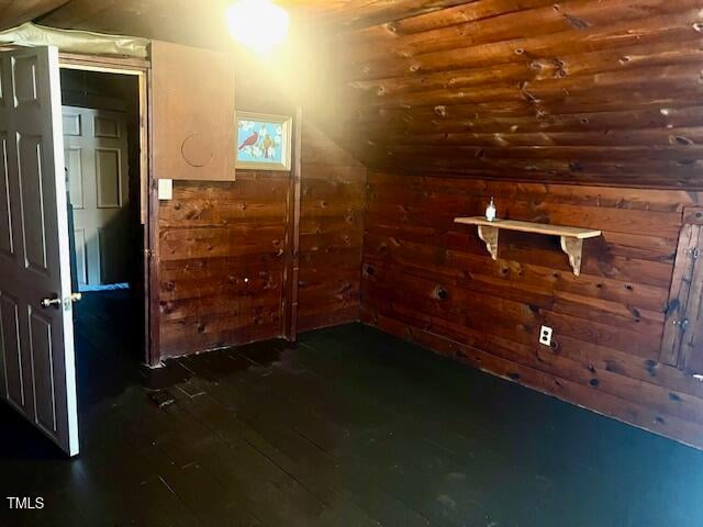 bonus room featuring lofted ceiling and wooden walls