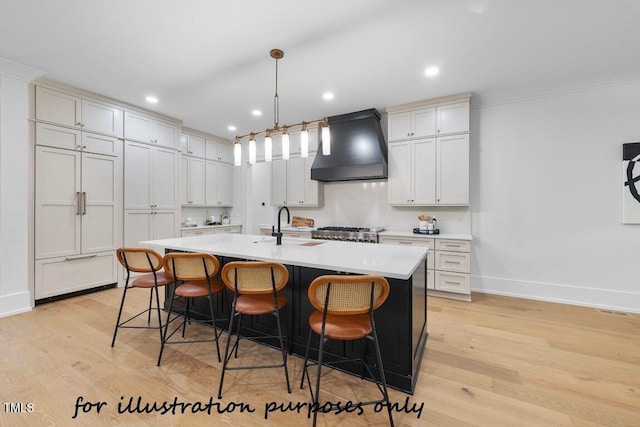 kitchen featuring premium range hood, a breakfast bar, light hardwood / wood-style flooring, a center island with sink, and pendant lighting