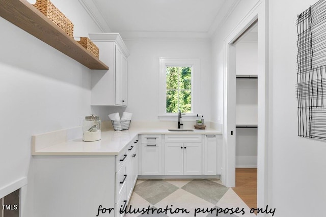 kitchen with sink, ornamental molding, and white cabinets