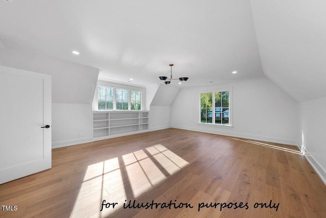 additional living space featuring vaulted ceiling, a healthy amount of sunlight, and light hardwood / wood-style floors