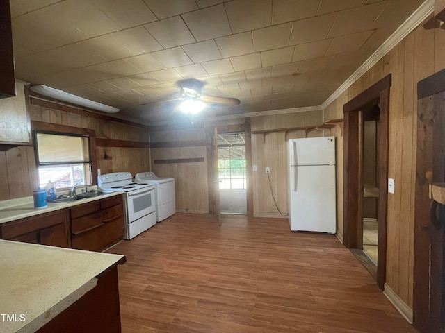 kitchen featuring light hardwood / wood-style flooring, wood walls, white appliances, and washer / dryer