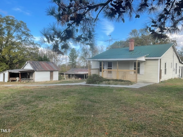 view of front facade with covered porch, a front yard, and an outdoor structure