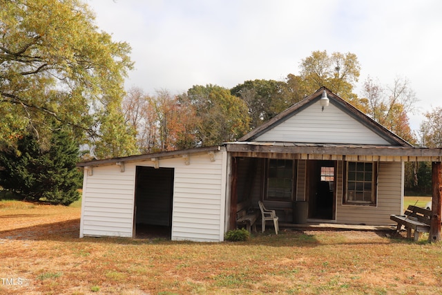 rear view of property with an outdoor structure and a yard