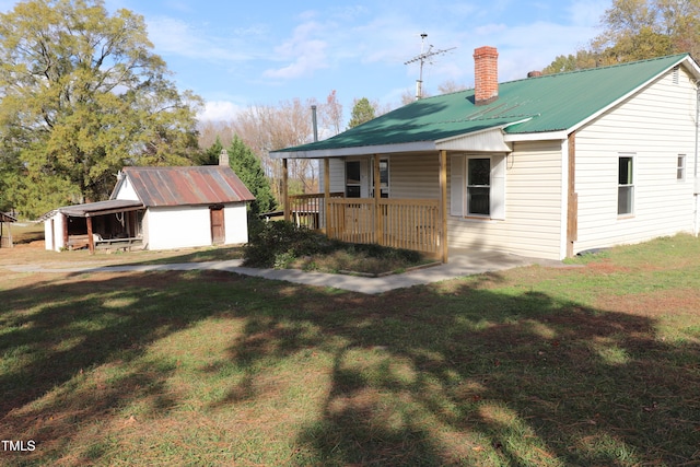 view of front facade with a shed, a front yard, and a porch