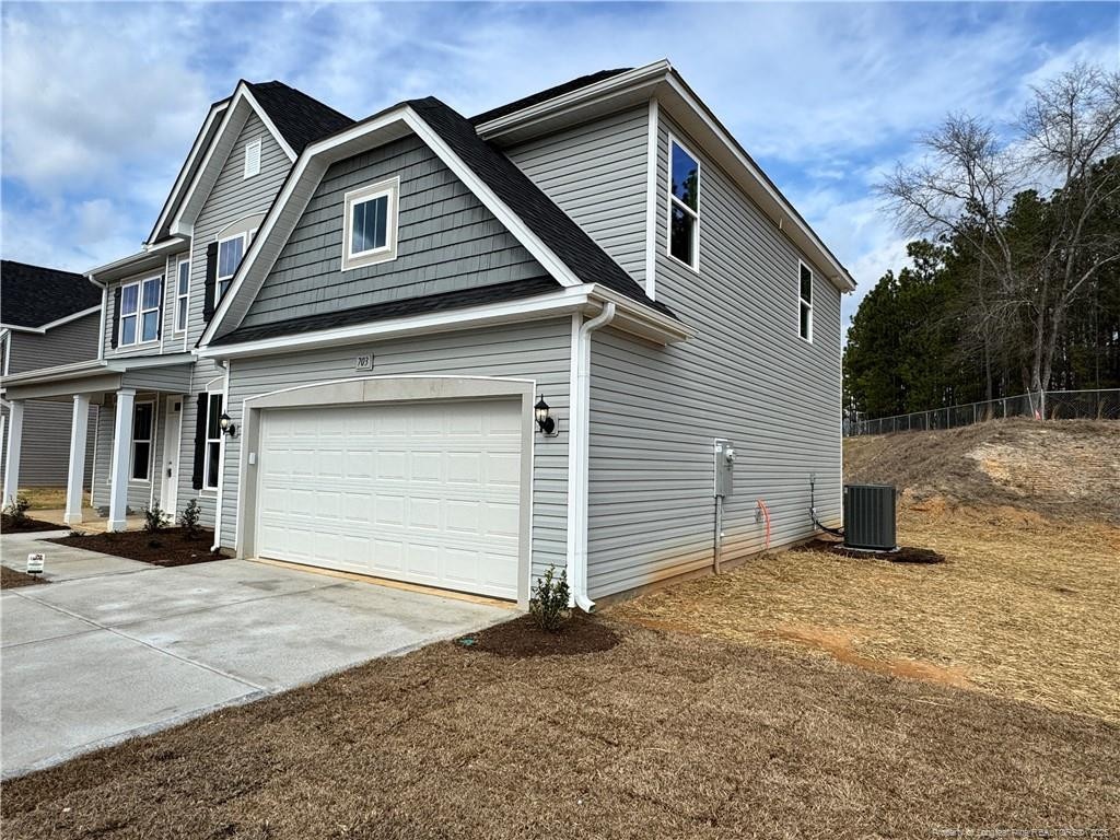 view of front of property with a garage and central AC